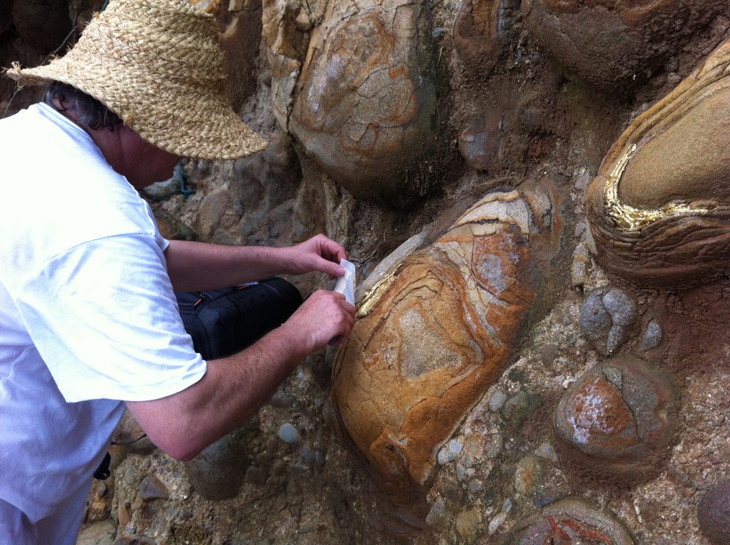 François JEKER appose de la feuille d'or sur des roches en Martinique